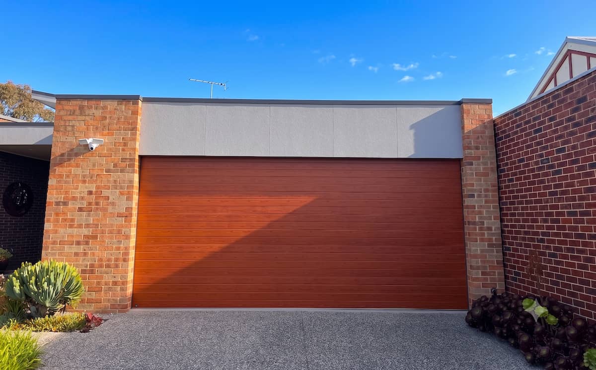 B&D Panelift Icon garage door in Seville wood grain profile featuring a red gum TimberCoat finish, professionally installed with stainless steel cables, perimeter weather seals, a B&D smart motor, and a B&D Auto-Lock system in Geelong by Ascent Garage Doors.